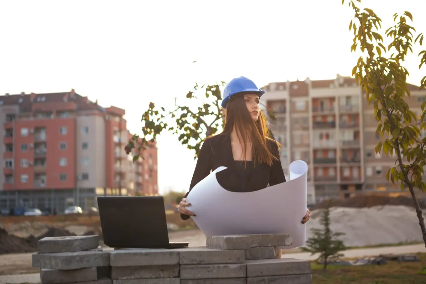 kobieta w kasku ochronnym w plenerze z planem i laptopem